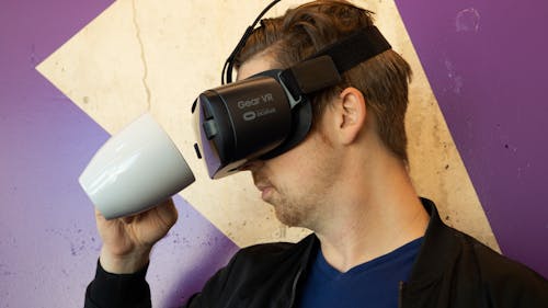 Mann, Der Virtual Reality Headset Trägt Und Einen Becher Hält