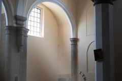 Calm church interior with sunlight streaming through arched windows onto empty pews.