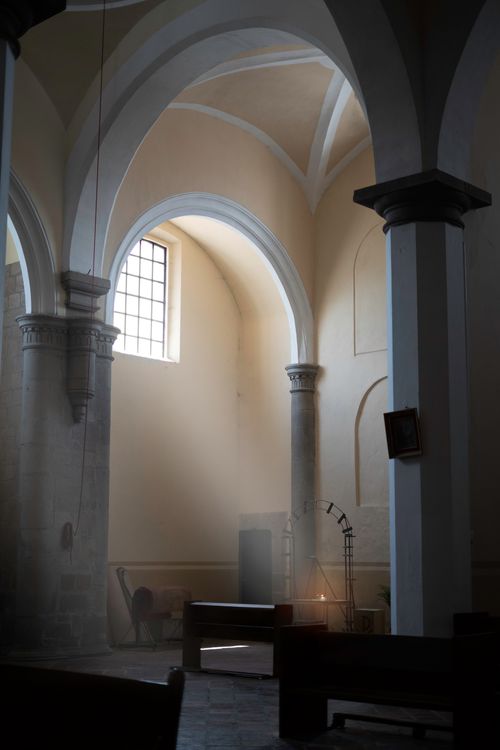 Free Calm church interior with sunlight streaming through arched windows onto empty pews. Stock Photo