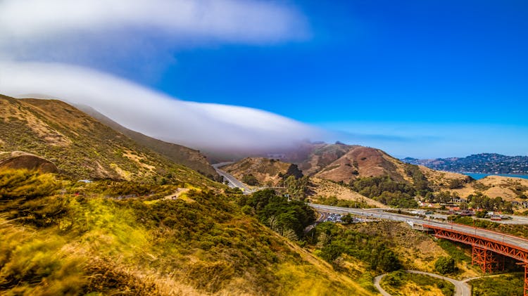 Photo Of A Mountains Landscape With A Road And A Red Bridge