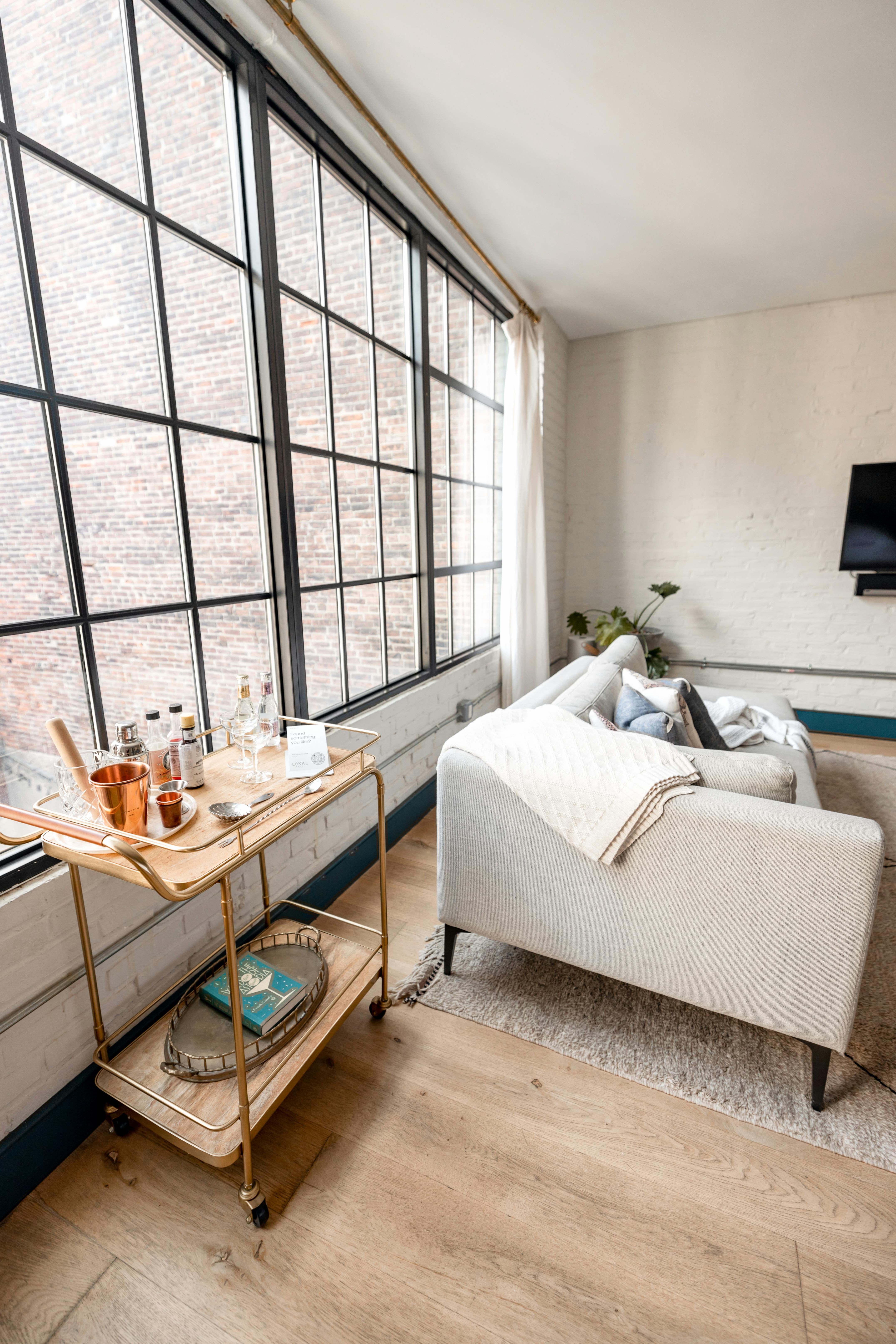 Bright living room with a stylish couch and beverage trolley.