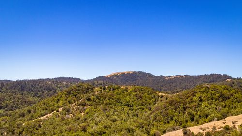 Free Scenic aerial view of verdant hills with a clear blue sky, perfect for travel and nature themes. Stock Photo