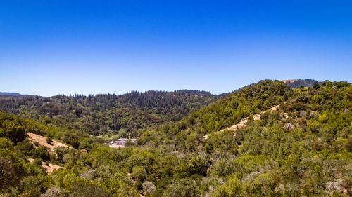 Free A breathtaking aerial view showcasing lush green hills under a clear blue sky. Stock Photo