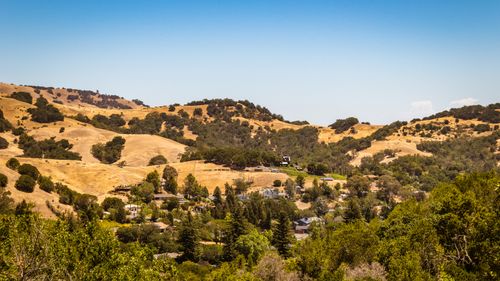 Free Beautiful rural landscape featuring golden hills and lush greenery under a clear sky. Stock Photo
