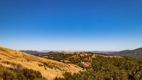 Free A scenic aerial view of rolling hills under a bright blue sky, offering expansive natural beauty. Stock Photo