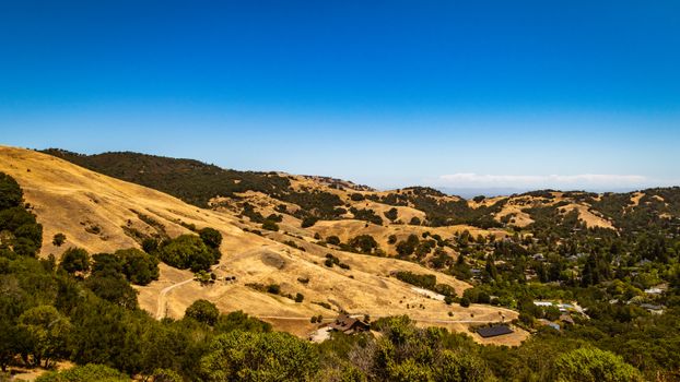 Aerial view of picturesque rolling hills with blue skies and scattered greenery.