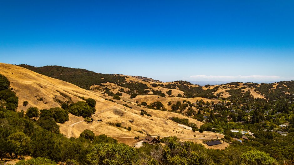 Aerial view of picturesque rolling hills with blue skies and scattered greenery.