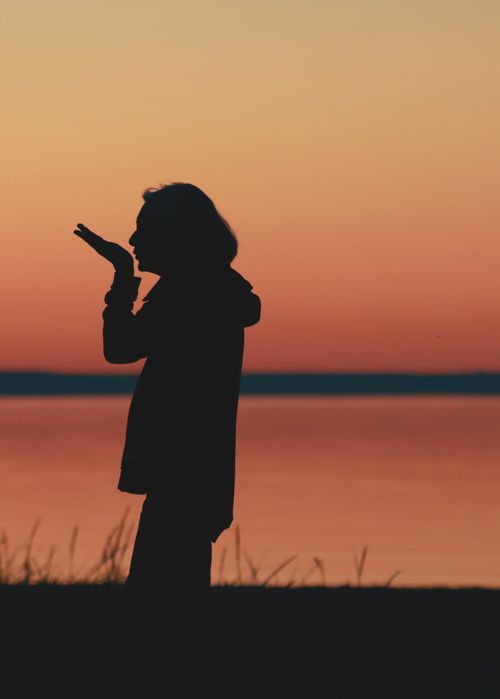 Free Silhouette of a person blowing a kiss against a vibrant sunset in Jönköping, Sweden. Stock Photo