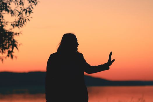 Silhouette of a person making a hand gesture against a vibrant sunset in Jönköping, Sweden.. pexels, silhouette, person