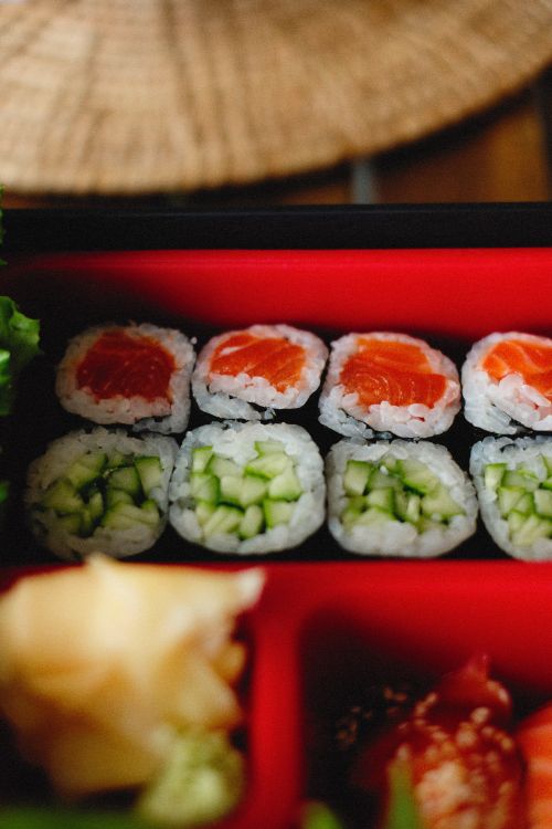 Free Close-up of assorted sushi rolls with salmon and cucumber in a vibrant bento box. Stock Photo