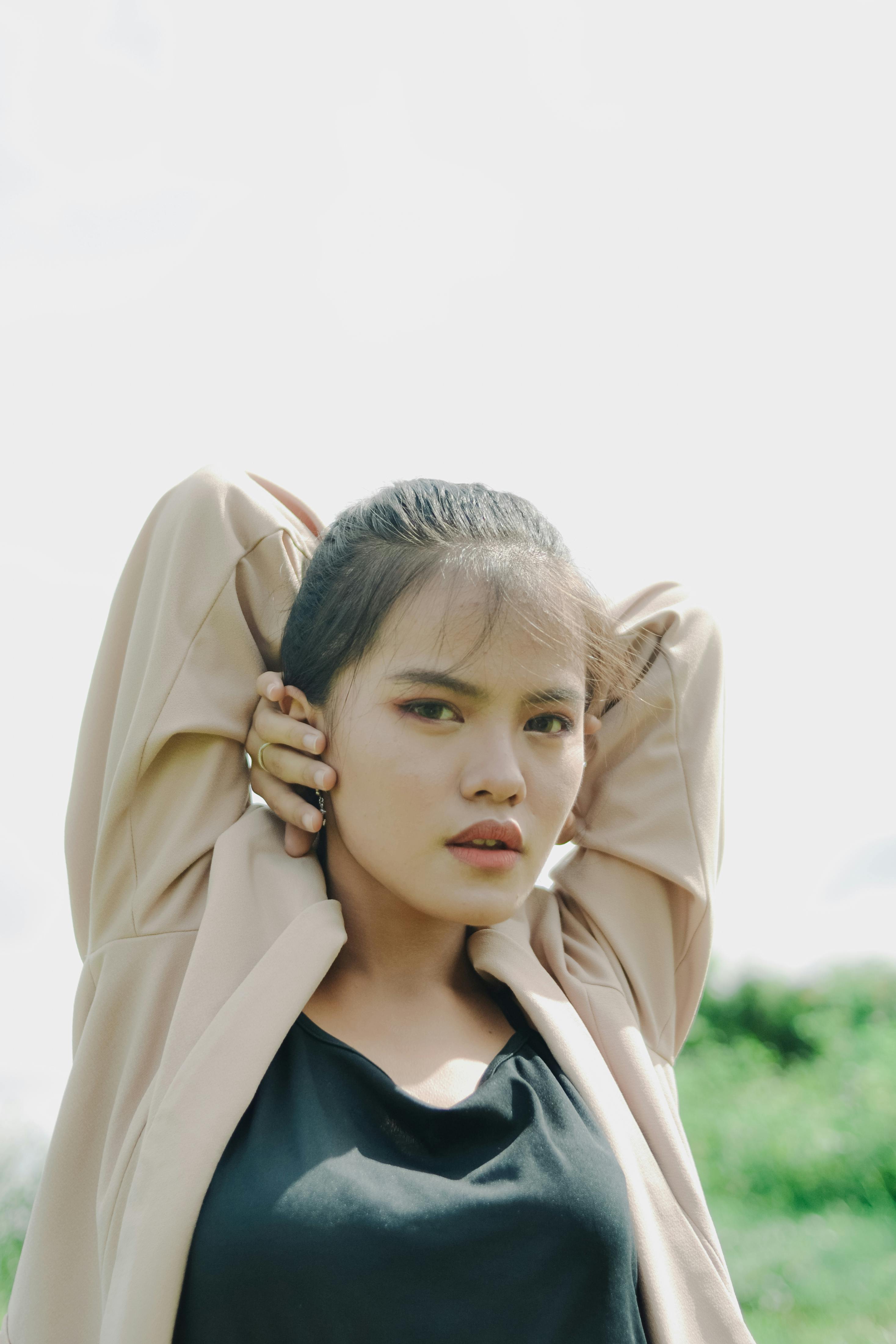 Natural light portrait of a woman posing with hands behind head outdoors in Indonesia.