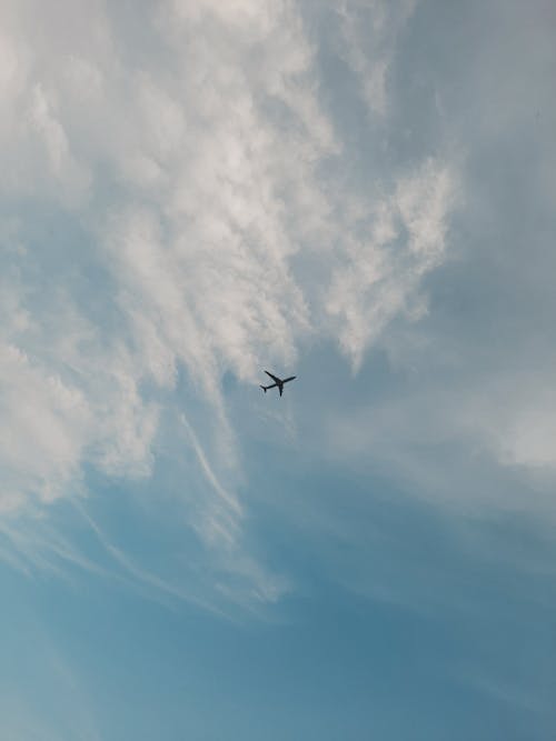 Photo of an Airplane Under White Clouds