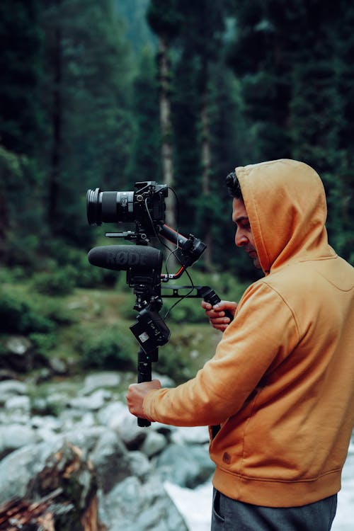 Photograph of a Man in a Hoodie Holding a Tripod
