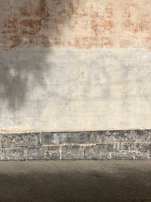 Free A textured brick wall with natural shadows creating a vintage and rustic feel, suitable for background use. Stock Photo