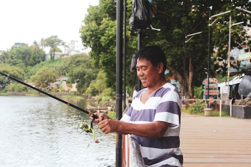Man in White and Blue Shirt Fishing on Lake