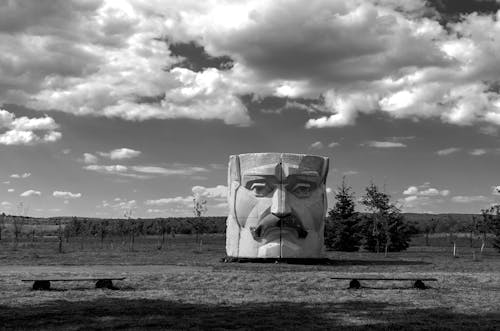 Black and White Photo of a Stone Sculpture on a Field, and Clouds in Sky