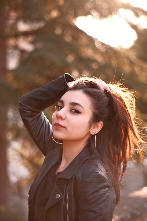 A Woman in a Leather Jacket Touching Her Hair