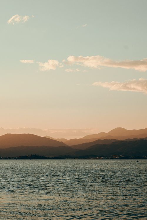 Free Peaceful twilight scene featuring mountains and the sea, offering tranquility. Stock Photo