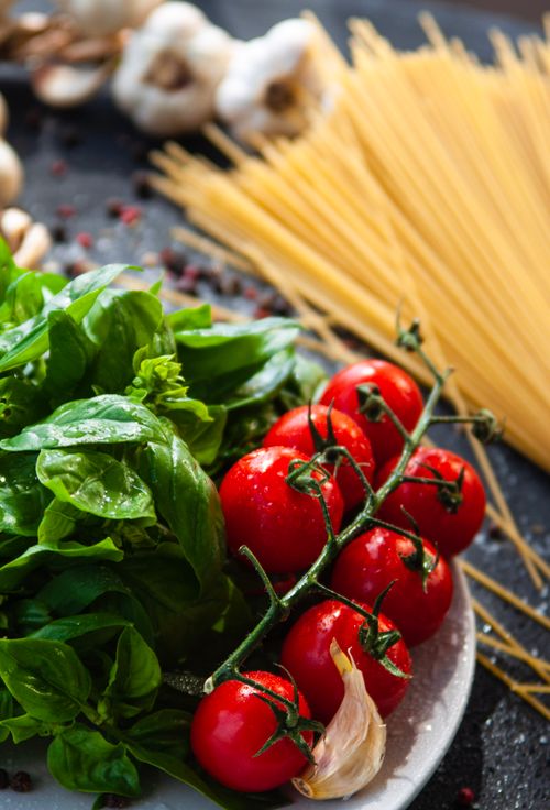 Free Close-up of fresh basil, vine tomatoes, and spaghetti for Italian pasta dishes. Stock Photo