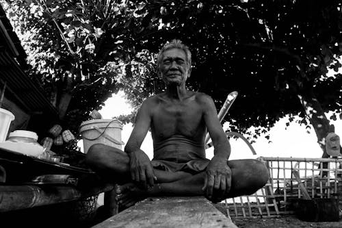 Grayscale Photo of a Shirtless Man Sitting