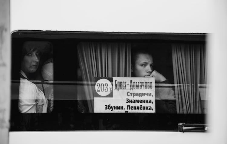 Grayscale Photo Of A Woman And A Boy Looking Out A Bus Window