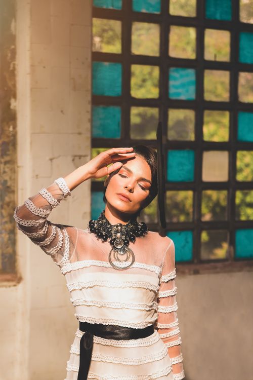 Free A woman in elegant attire poses indoors in Rio de Janeiro, wearing a statement necklace. Stock Photo