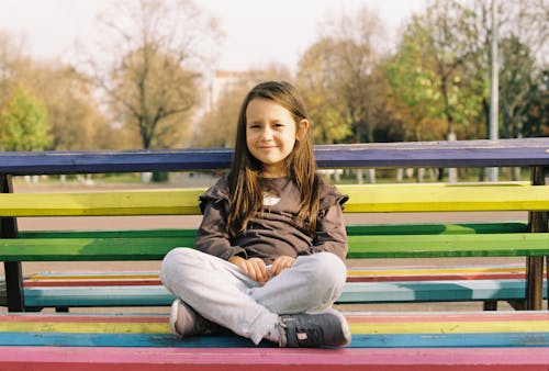 Cute Girl Sitting on a Colorful Bench