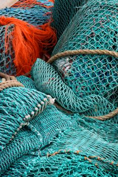 Close-up of colorful fishing nets with orange and teal hues intertwined.