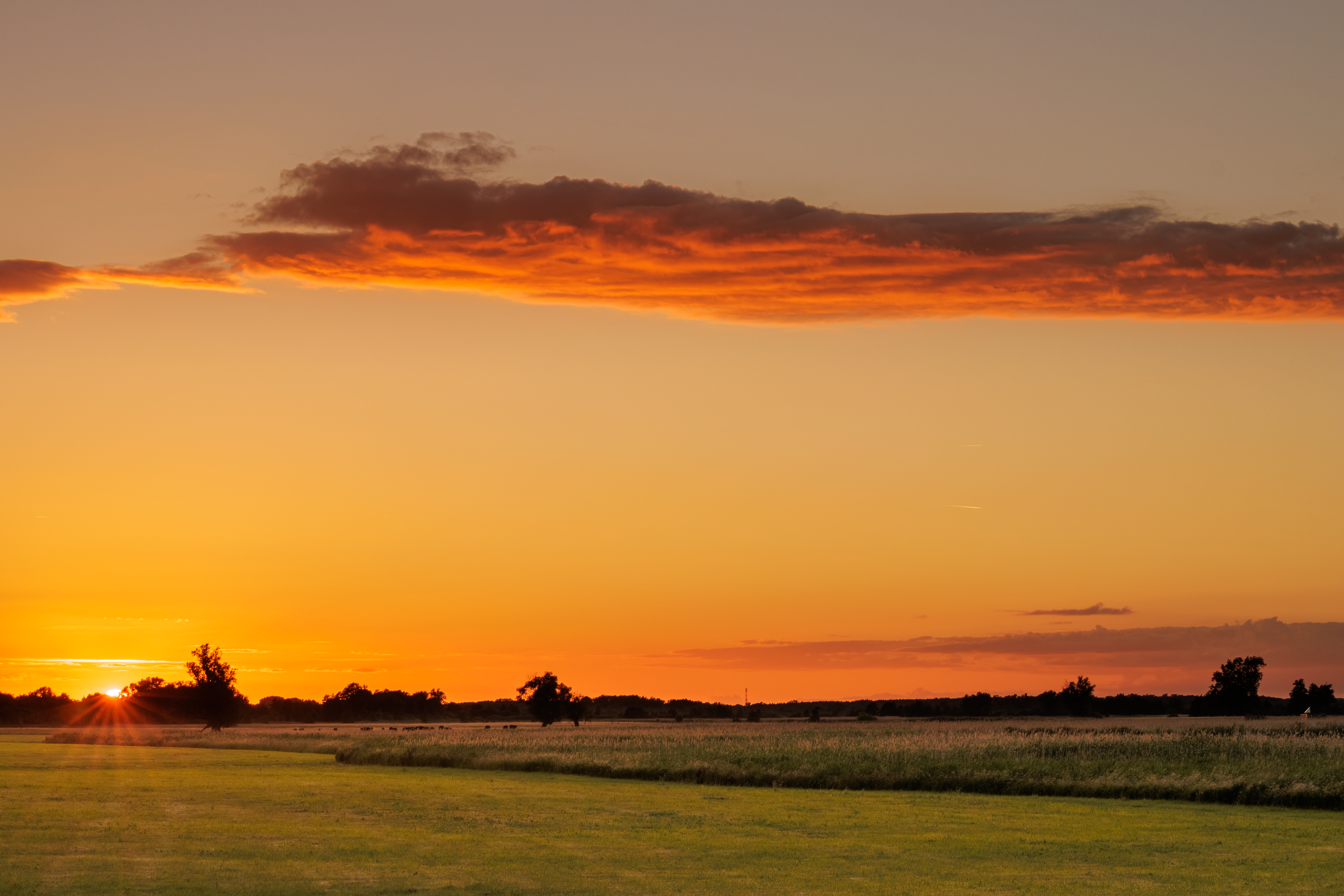 sunset sky with light breaking through clouds over a calm landscape