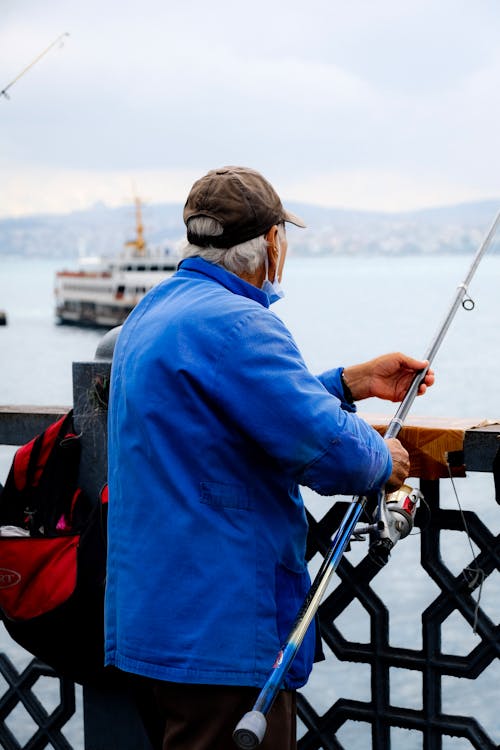 Elderly Man in Blue Jacket Holding a Fishing Rod