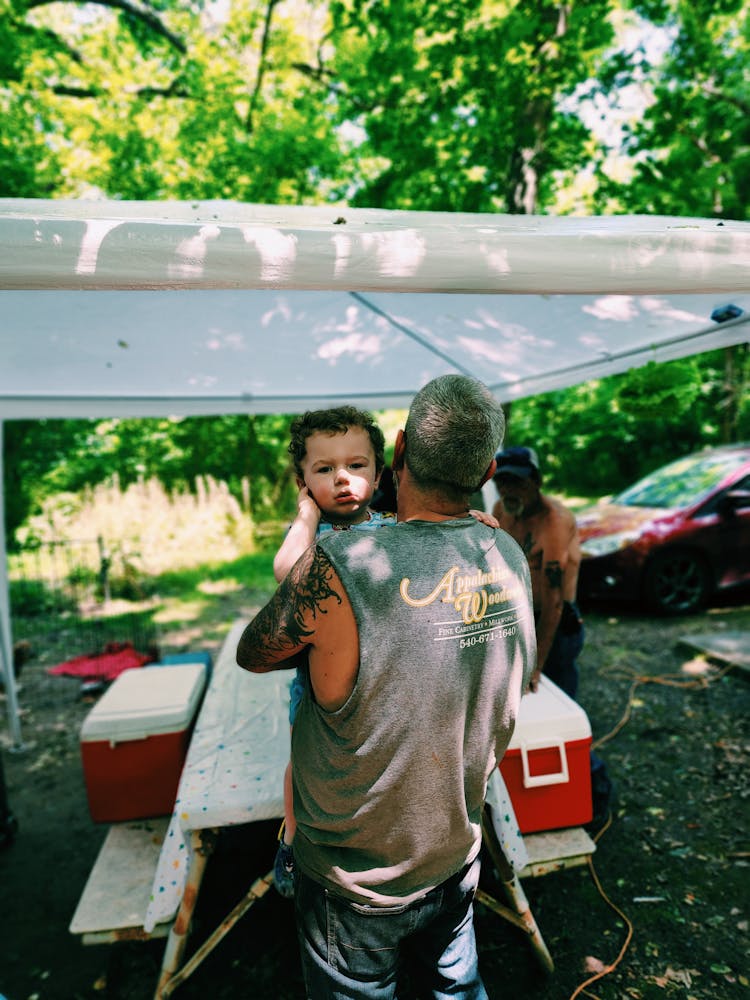 Man Holding Baby While Setting Up Picnic