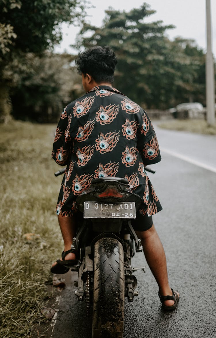 Back View Of A Young Man Wearing Patterned Shirt Sitting On A Motorbike