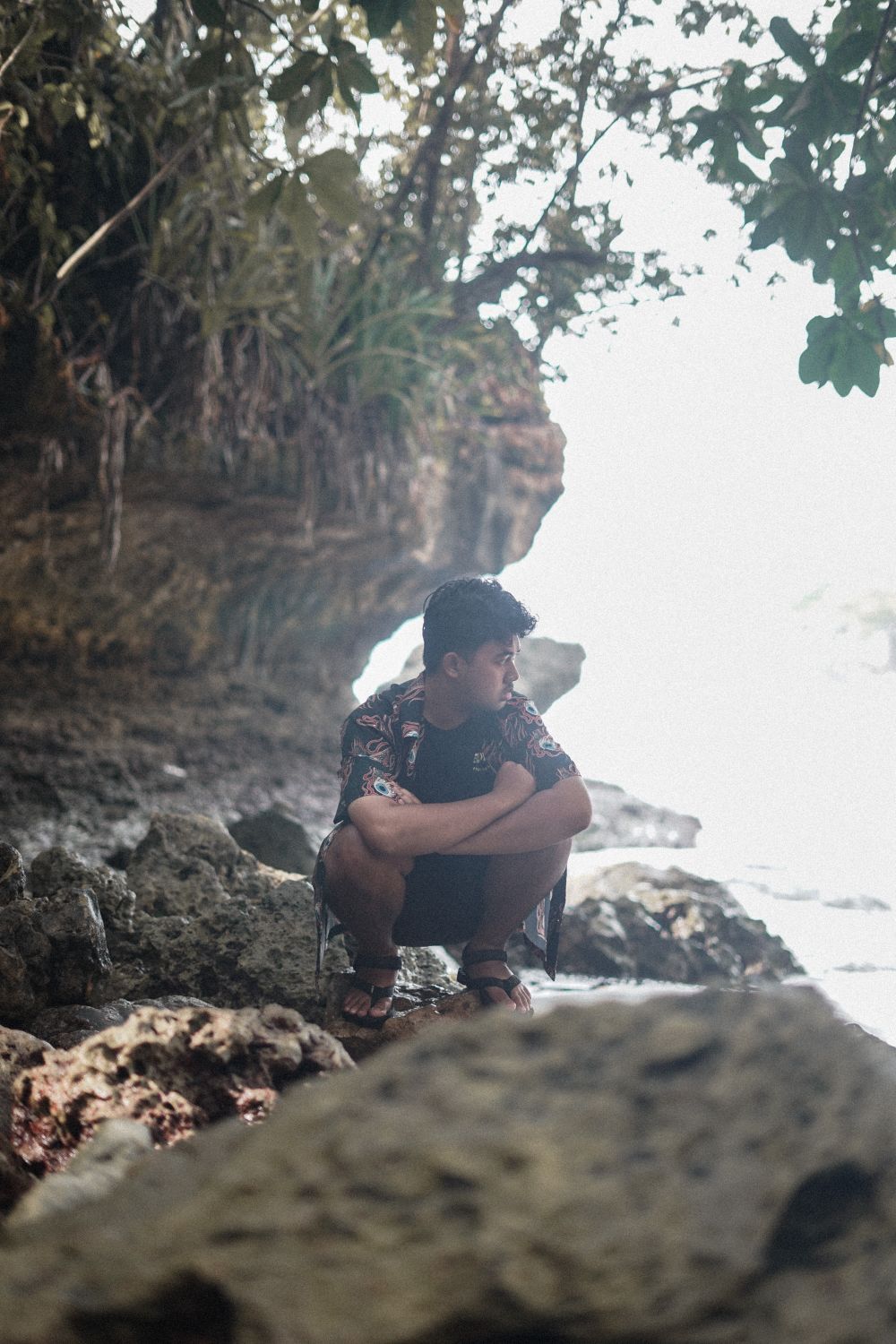 Man Crouching on Rocks by Sea Shore · Free Stock Photo