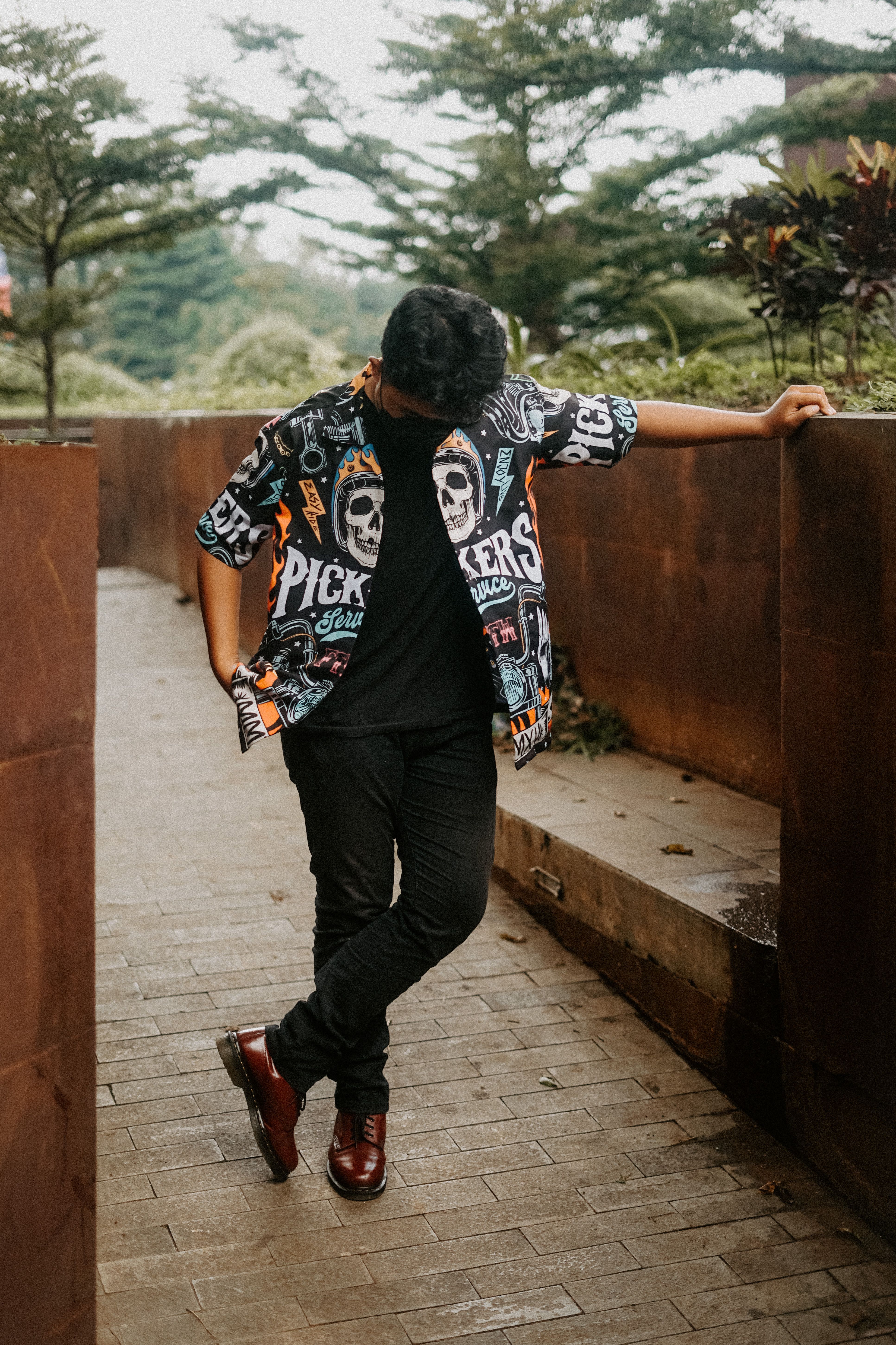 Stylish man in patterned shirt posing in urban park setting.