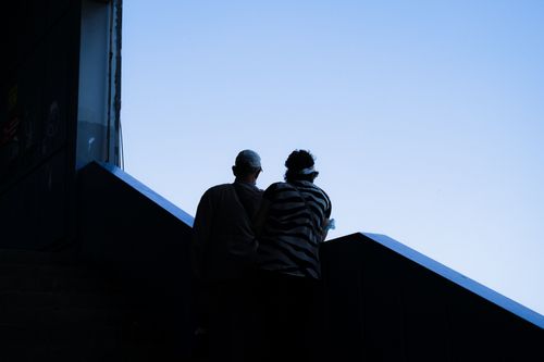 Free A couple silhouetted against a clear blue sky, standing closely on outdoor stairs. Stock Photo
