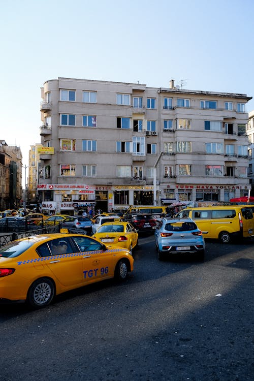 Yellow Taxi Cab on Road Near White Concrete Building