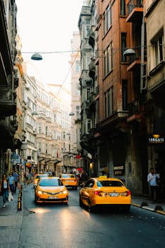 Street scene with yellow taxis and pedestrians in an urban setting, capturing city life and architecture.