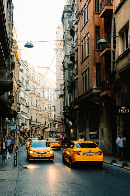 Street scene with yellow taxis and pedestrians in an urban setting, capturing city life and architecture.