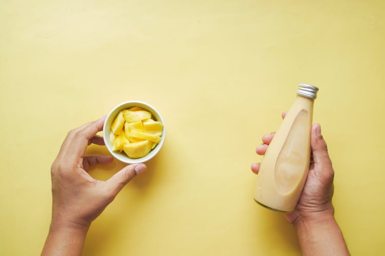 Hands Holding Yellow Bottle And Fruit