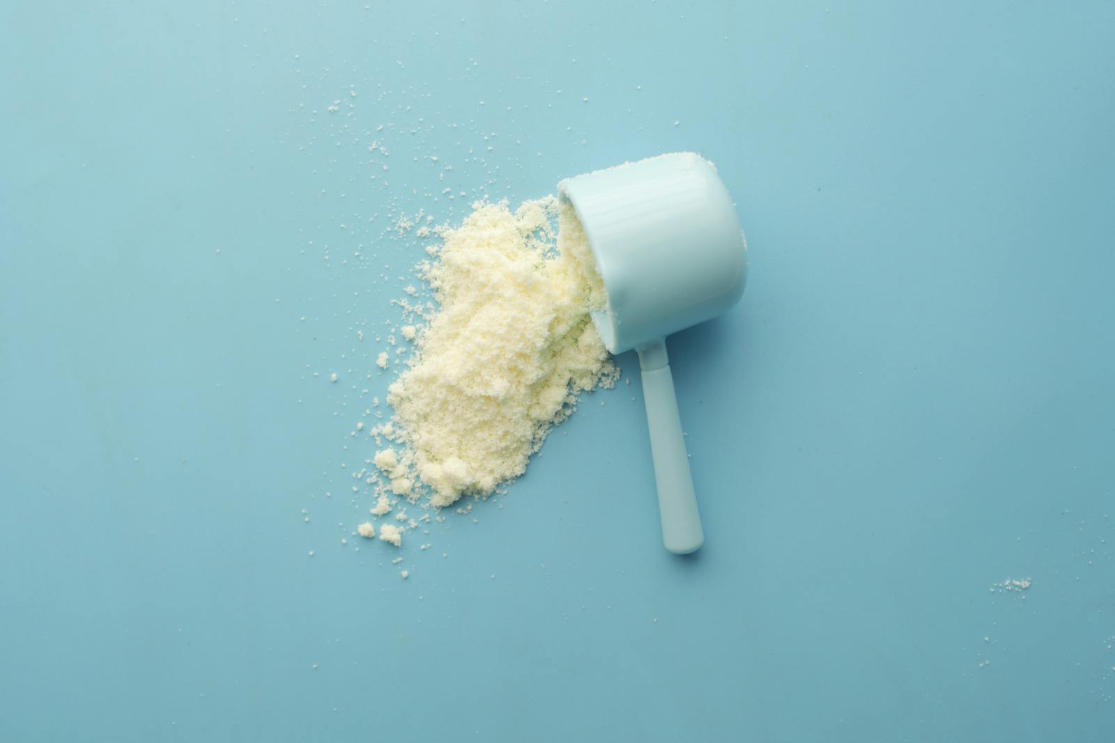 Minimal white supplement powder and scoop on a light background