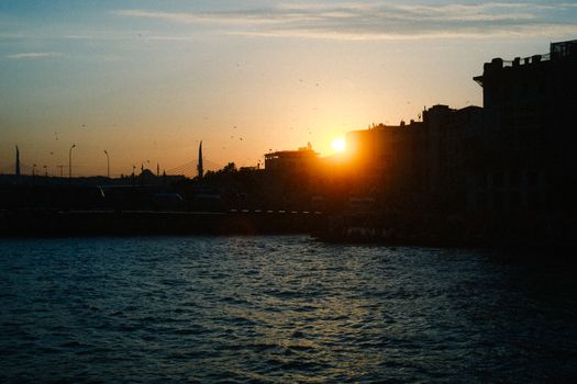 Beautiful sunset behind city skyline with waterfront view, creating a serene silhouette effect.