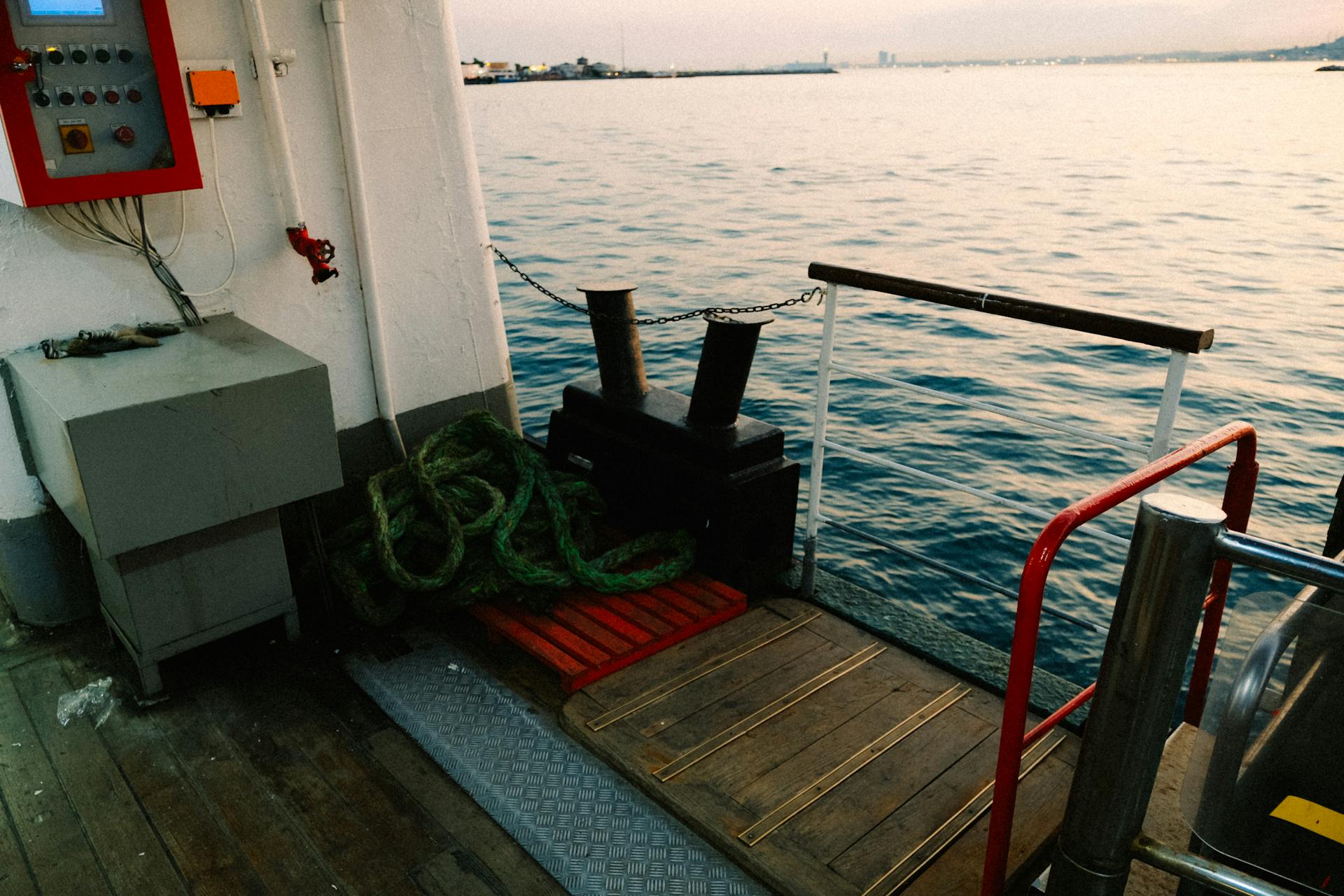 A serene scene on a ferry deck at sunset, docked at the harbor.