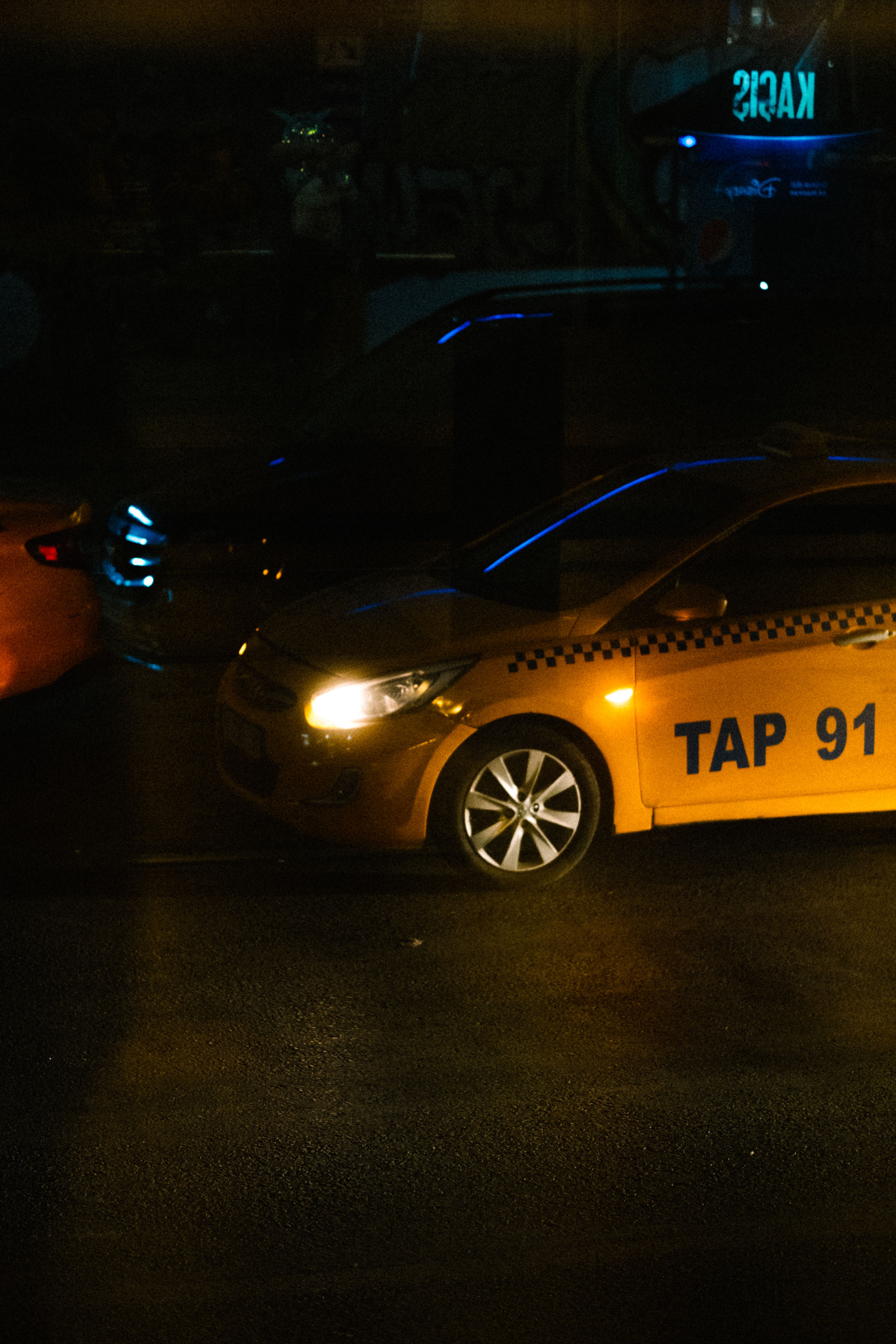City street at night with yellow taxi under neon lights
