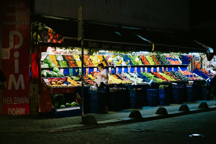 Woman Buying Fruit From Market At Night