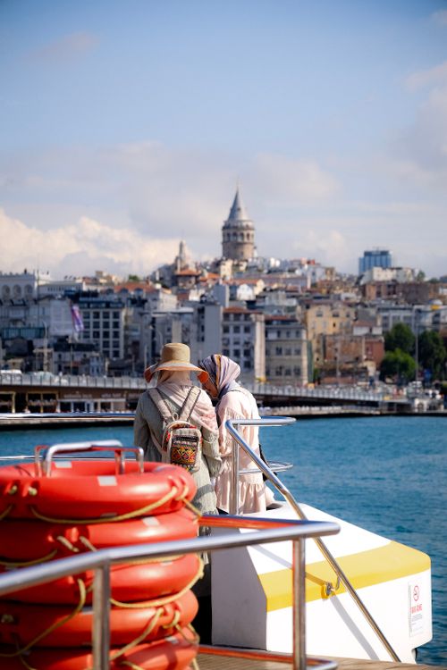Free Two women enjoy the scenic view of Galata Tower from a ferry on the Bosphorus in Istanbul, Turkey. Stock Photo