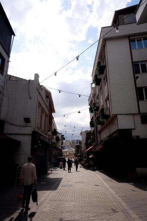 Free A lively narrow alley with string lights, showcasing urban architecture and pedestrians. Stock Photo