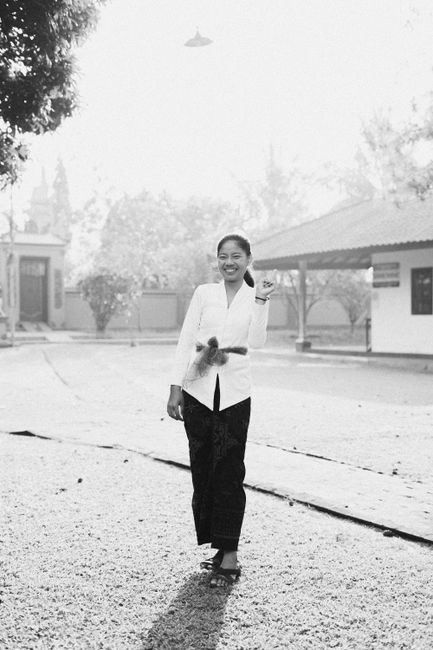 Smiling woman walks outside on a sunny day in a black and white photo.