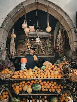 Man selling fresh fruits at a vibrant market stall with hanging decorations.