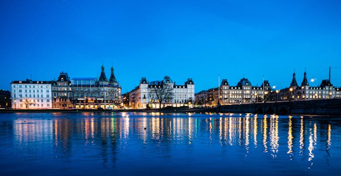 Stunning Copenhagen cityscape at dusk, featuring illuminated architecture reflected on water.