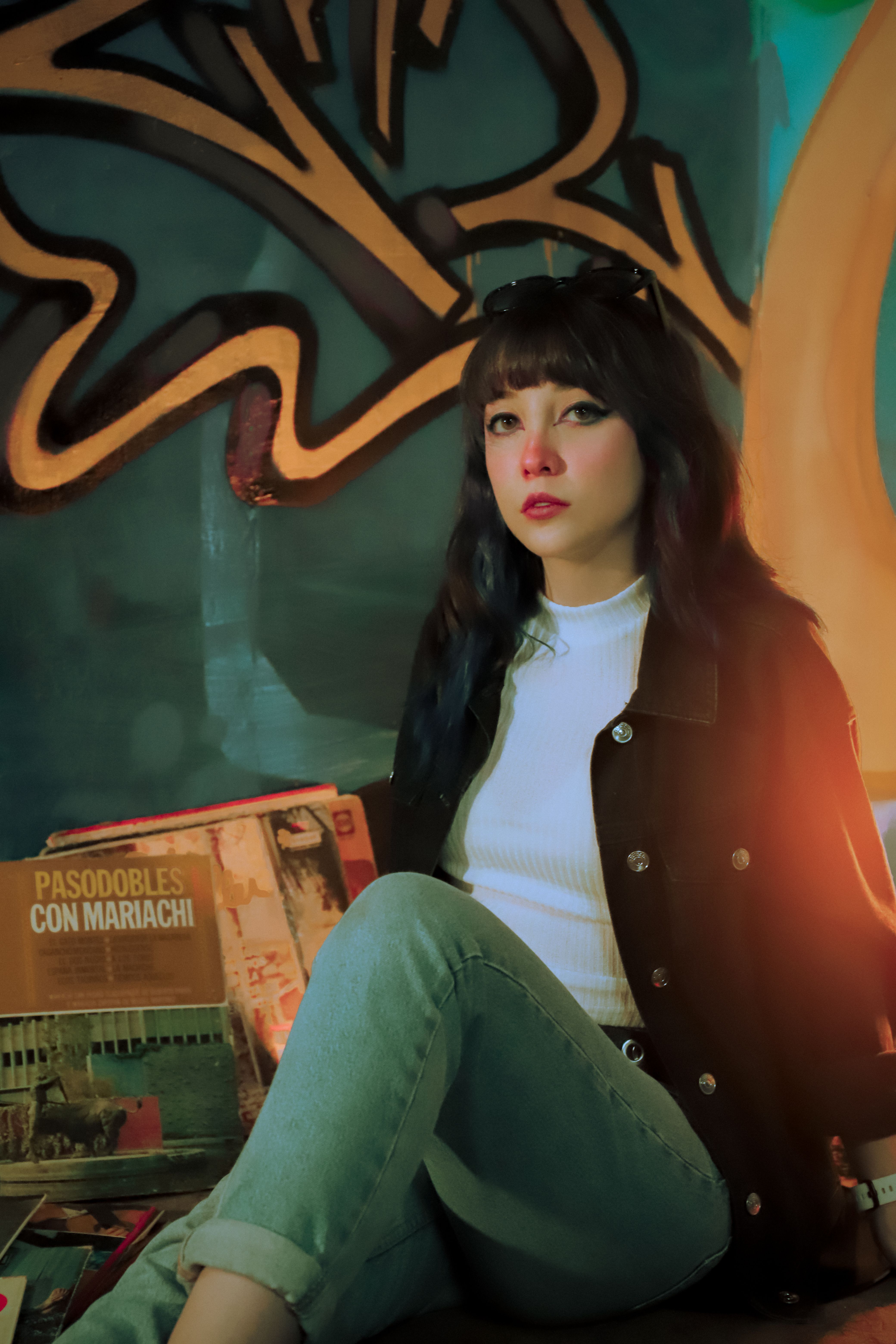 Stylish woman in casual attire poses by graffiti in Ciudad de México.